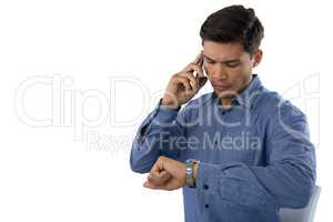 Businessman looking time while talking on smartphone