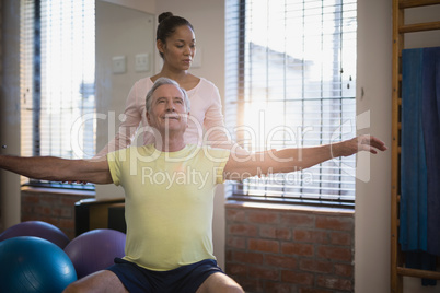 Female therapist looking at male patient sitting with arms outstretched