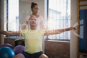 Female therapist looking at male patient sitting with arms outstretched