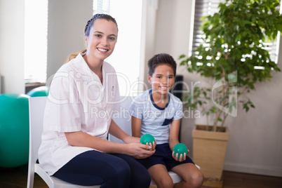 Portrait of smiling female therapist and boy holding stress balls