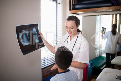 Female therapist holding x-ray while looking at boy