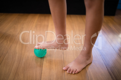 Low section of boy standing while stepping on stress ball