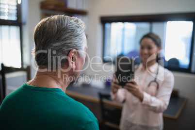 Rear view of senior male patient being photographed by female therapist