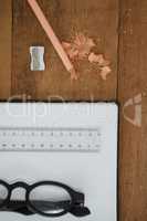 Book, pencil, spectacles, scale, pencil and sharpener on wooden table