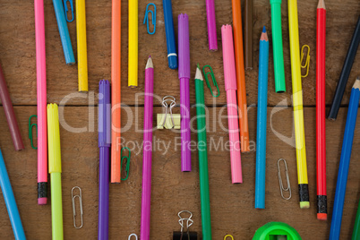 Various color pencil and paper clip on wooden table