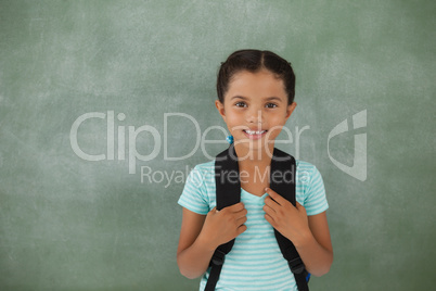 Young girl with bagpack against chalk board