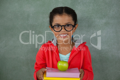 Young girl in glasses holding apple and books