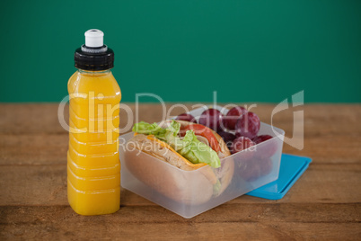 Tiffin box with fruit and sandwich on table