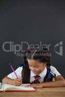 Schoolgirl doing her homework against chalkboard