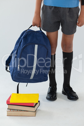 Schoolboy standing with school bag and books on white background