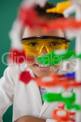 Smiling schoolboy experimenting molecule model in laboratory