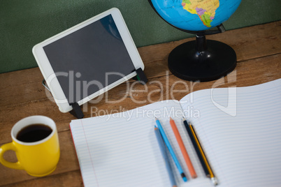 Digital tablet and globe on table in classroom