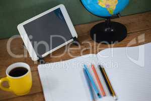 Digital tablet and globe on table in classroom