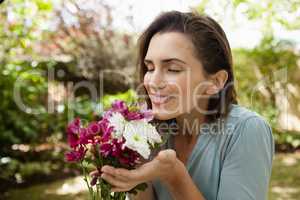 Smiling beautiful woman with eyes closed smelling flowers