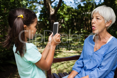 Girl taking photograph of grandmother sticking out tongue