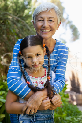 Portrait of smiling senior woman embracing granddaughter