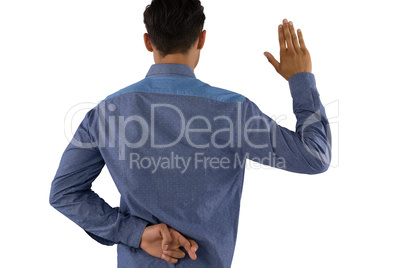 Rear view of businessman waving hand with crossed fingers