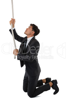 Side view of businessman pulling rope while kneeling