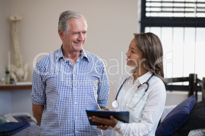 Smiling senior male patient and female therapist discussing file