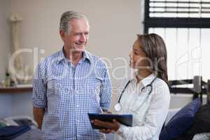 Smiling senior male patient and female therapist discussing file