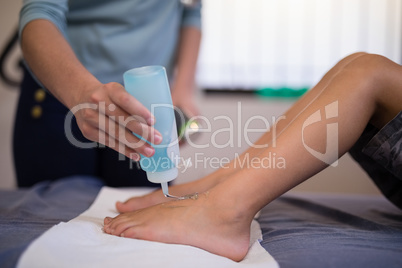 Female therapist pouring scanning gel on feet of boy