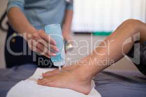 Female therapist pouring scanning gel on feet of boy