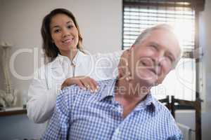 Portrait of smiling female therapist giving neck massage to senior patient