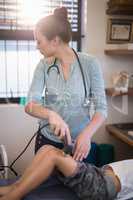 Female therapist using ultrasound machine on knee of boy