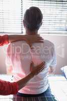 Rear view of senior male patient receiving back massage from female therapist