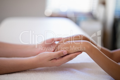 Young female therapist examining hands of boy on white towel