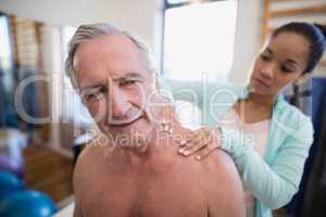 Shirtless male patient receiving neck massage from female therapist