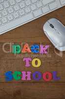 Keyboard, mouse and block letter with back to work text on wooden background