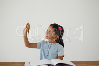 Young girl holding her pencil against white background