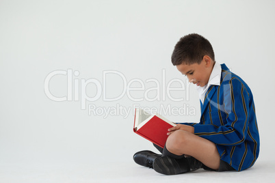 Schoolboy reading book on white background