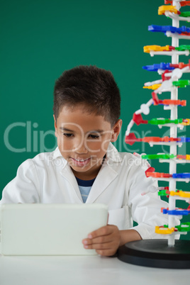 Smiling schoolboy using digital tablet in laboratory