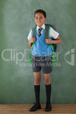 Schoolboy standing in front of chalkboard in classroom