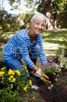 Portrait of smiling senior woman planting flowers