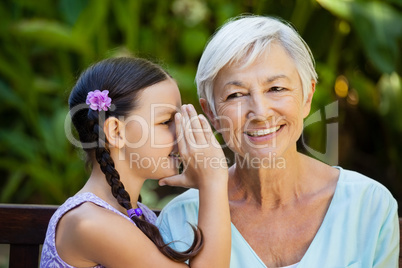 Granddaughter whispering in ears of smiling grandmother