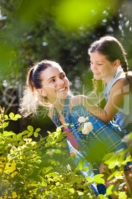 Smiling mother giving piggyback ride to daughter on sunny day