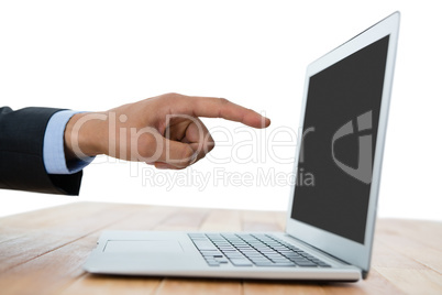 Cropped hand of businessman pointing on laptop