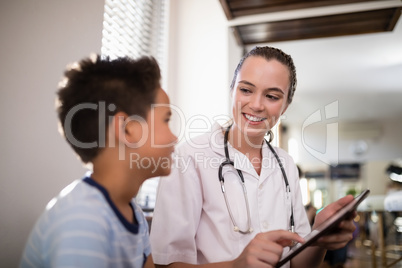 Smiling female therapist showing digital tablet to boy