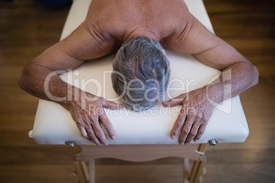 High angle view of shirtless senior male patient lying on bed