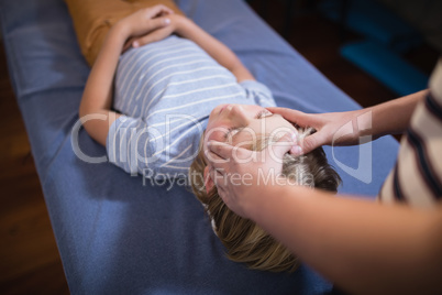High angle view of female therapist giving head massage to boy