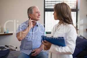 Senior male patient showing neck sprain to female doctor with file