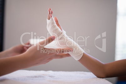 Close-up of female therapist wrapping bandage on hand