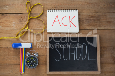 School supplies, alarm clock and measuring tape on wooden table
