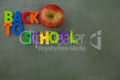 Block letters and apple arranged on chalkboard