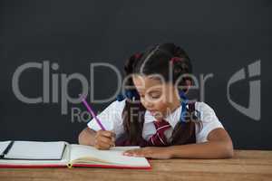 Schoolgirl doing her homework against chalkboard