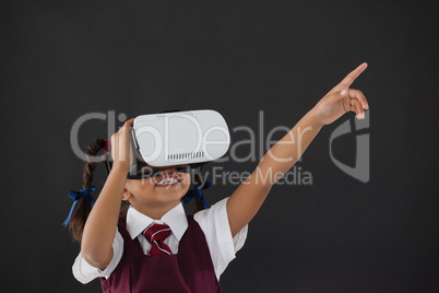 Schoolgirl using virtual reality headset against blackboard