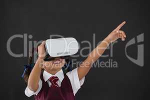 Schoolgirl using virtual reality headset against blackboard